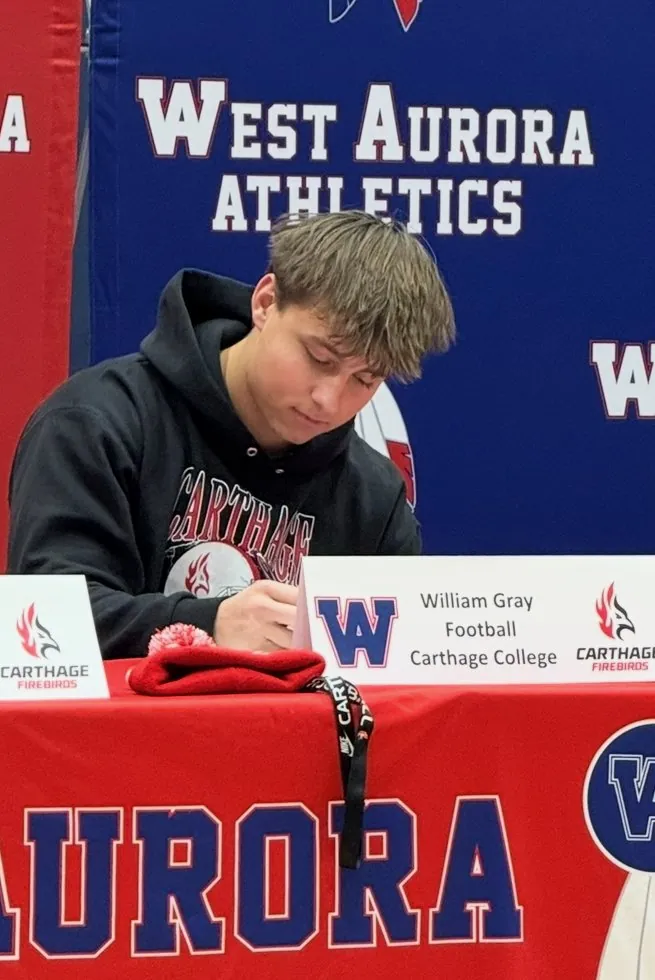 Will signing his papers at the West Aurora signing table behind his Carthage name card