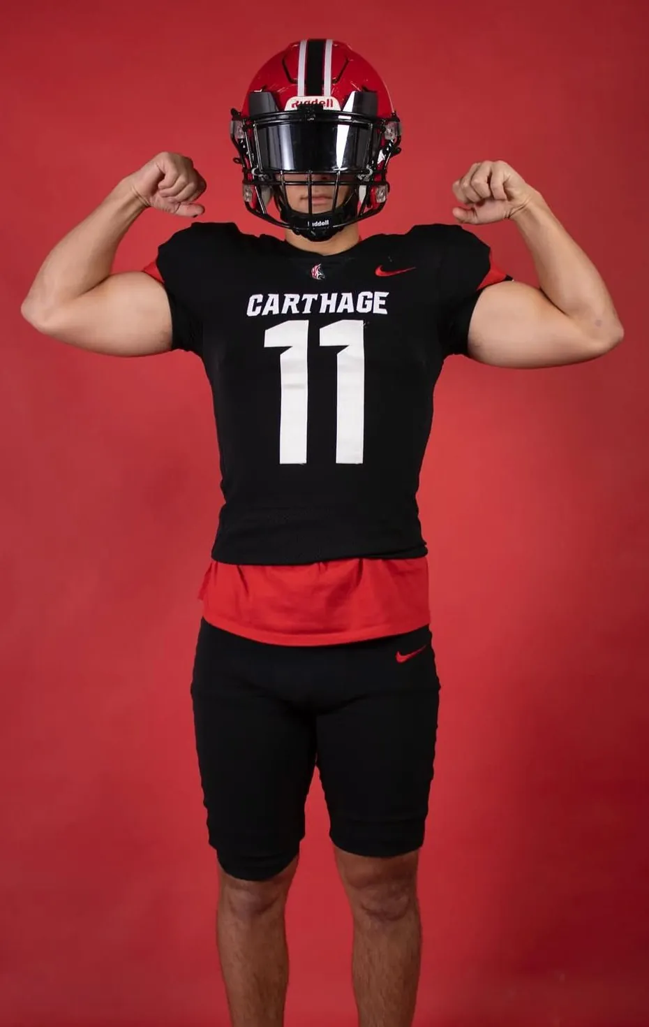 Will flexing in a black Carthage jersey against a red backdrop